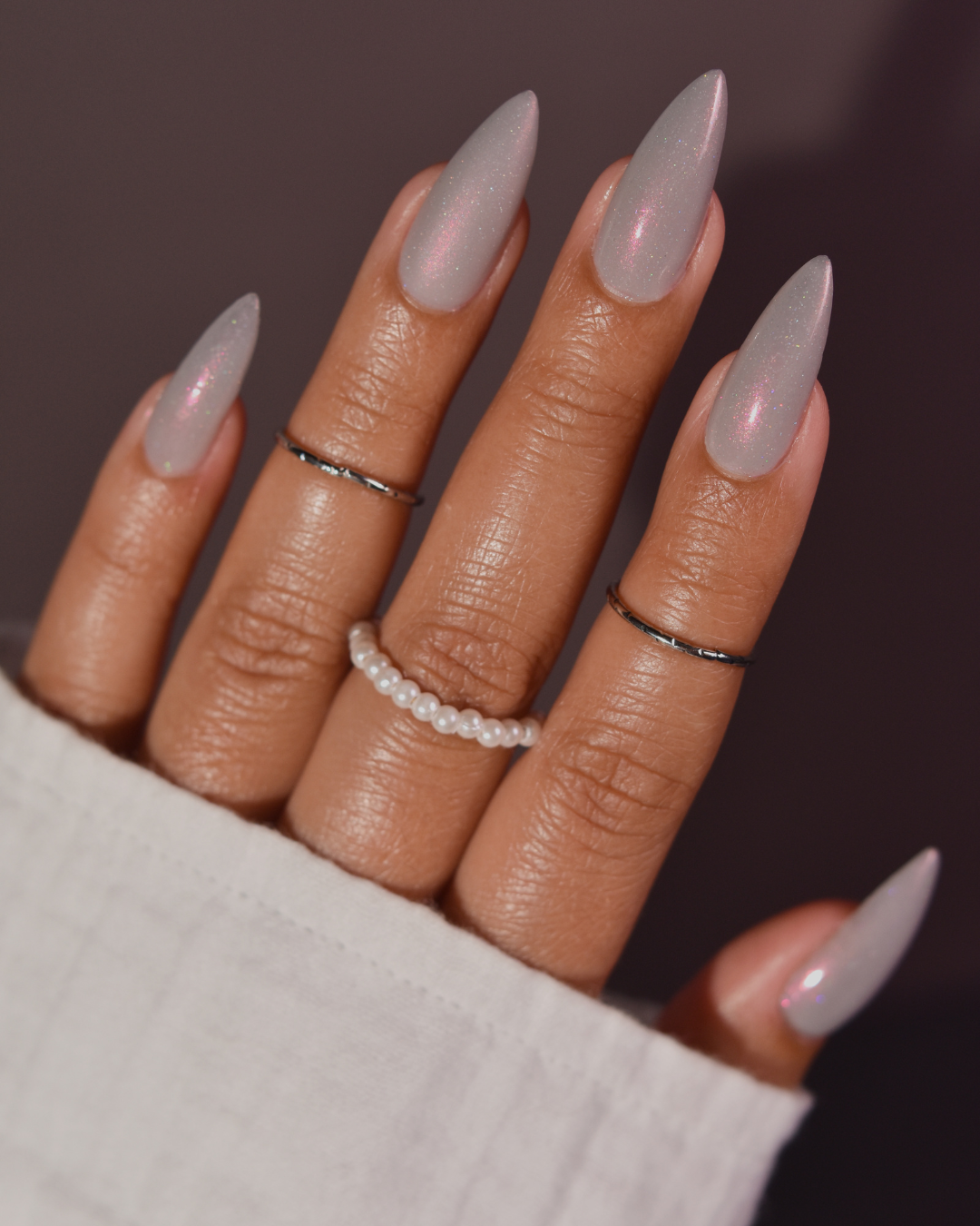A close-up of a hand with long, almond-shaped nails painted in a glossy grey shade.