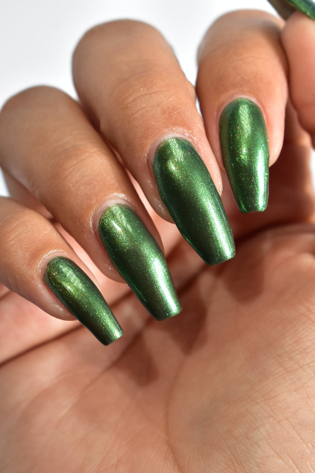 A manicured hand wearing a green nail polish.