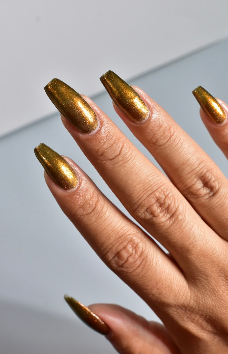 A hand with a copper shimmer manicure.