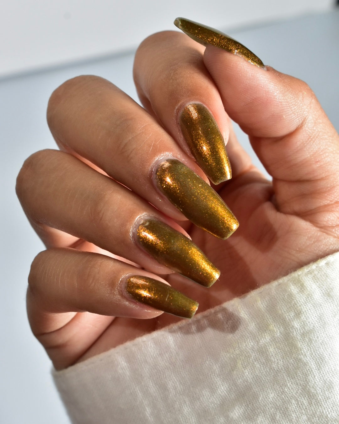 A hand with a copper shimmer nail polish manicure.