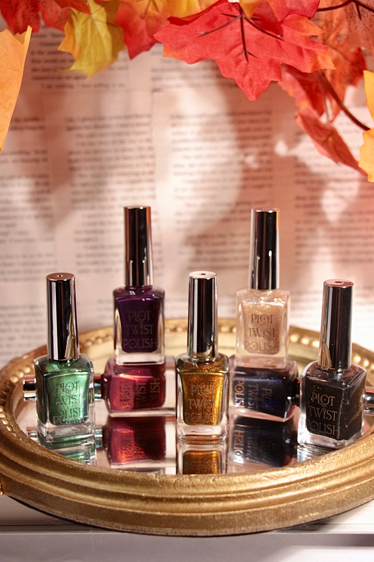7 nail polishes sitting on a mirror with leaves in the background