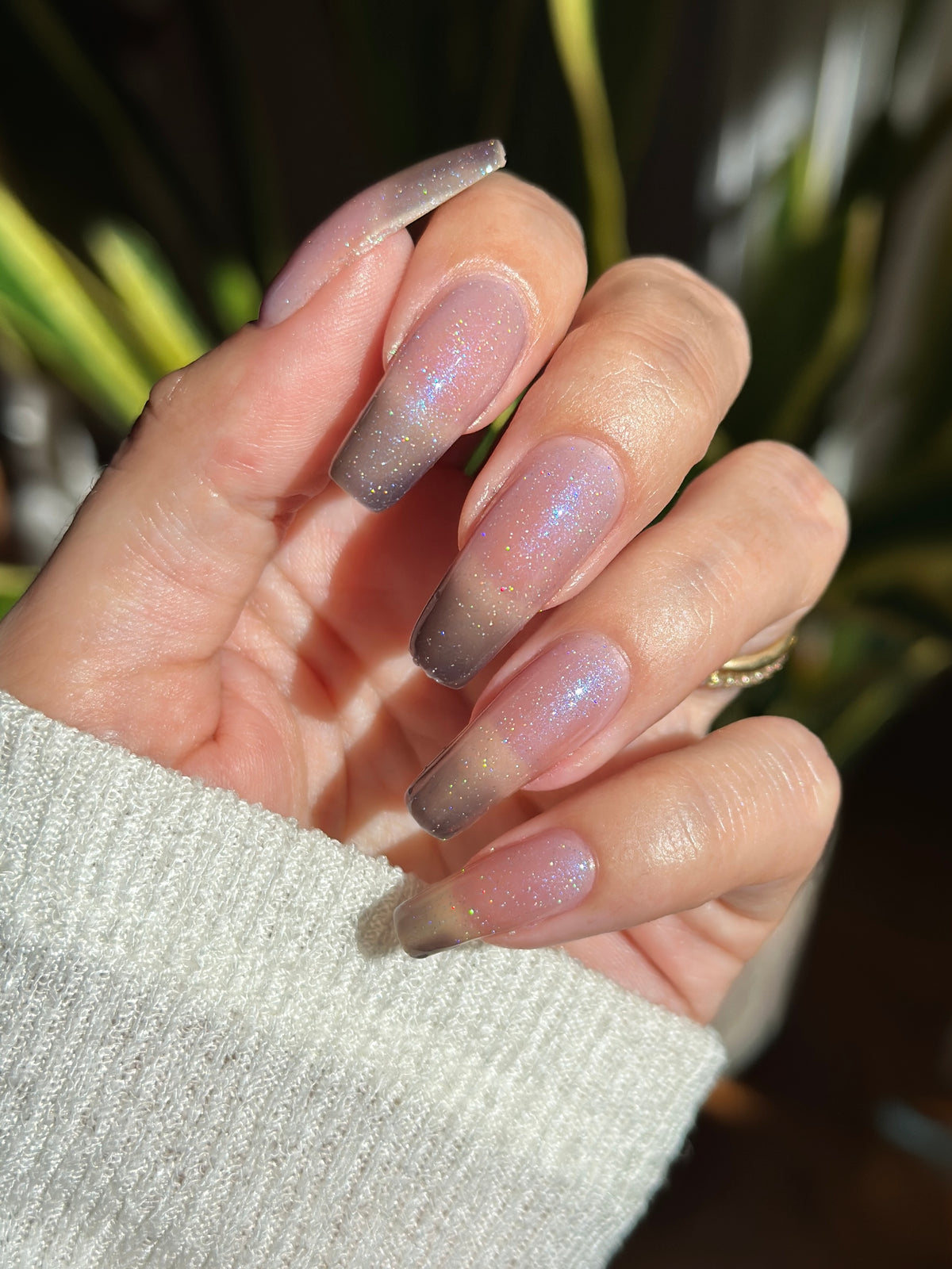A manicured hand with a translucent shimmery nail polish base and blue nail tips.
