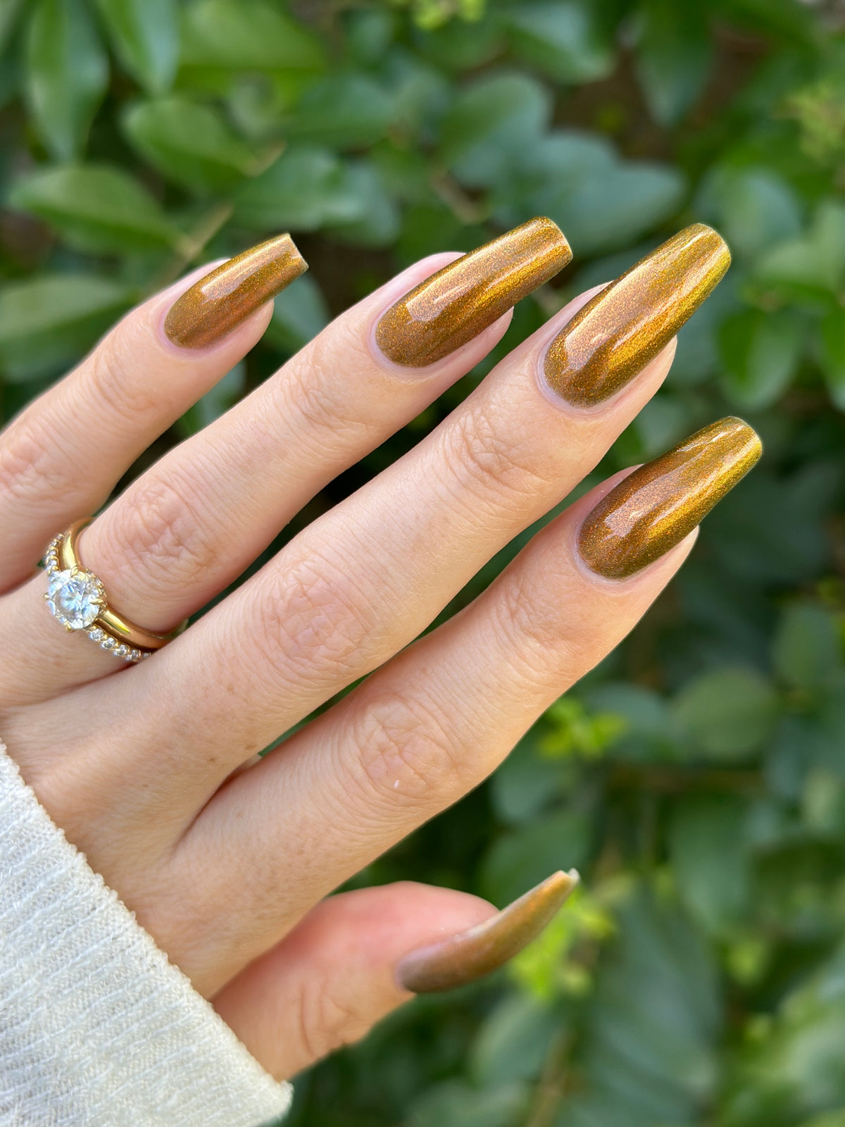 A hand with a copper shimmer manicure.