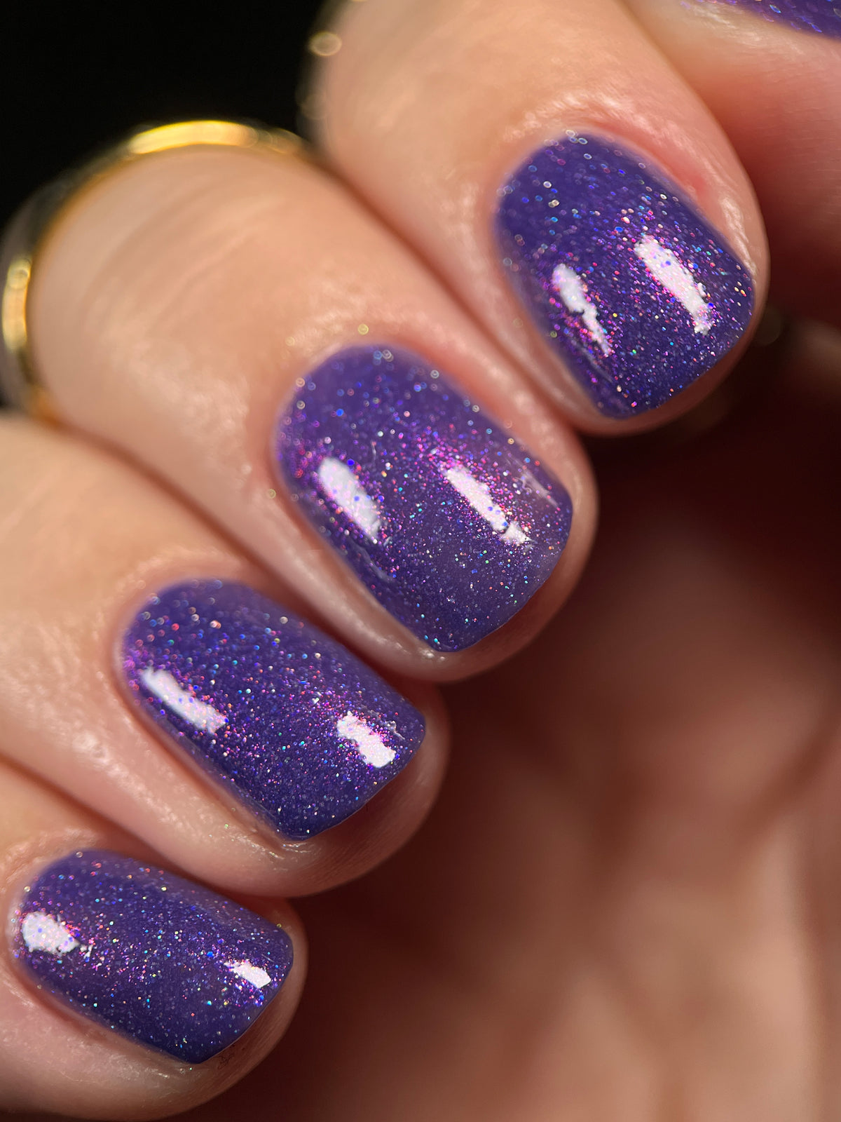 Close-up of fingernails painted with a glittery purple nail polish showing fine shimmer and a glossy finish.
