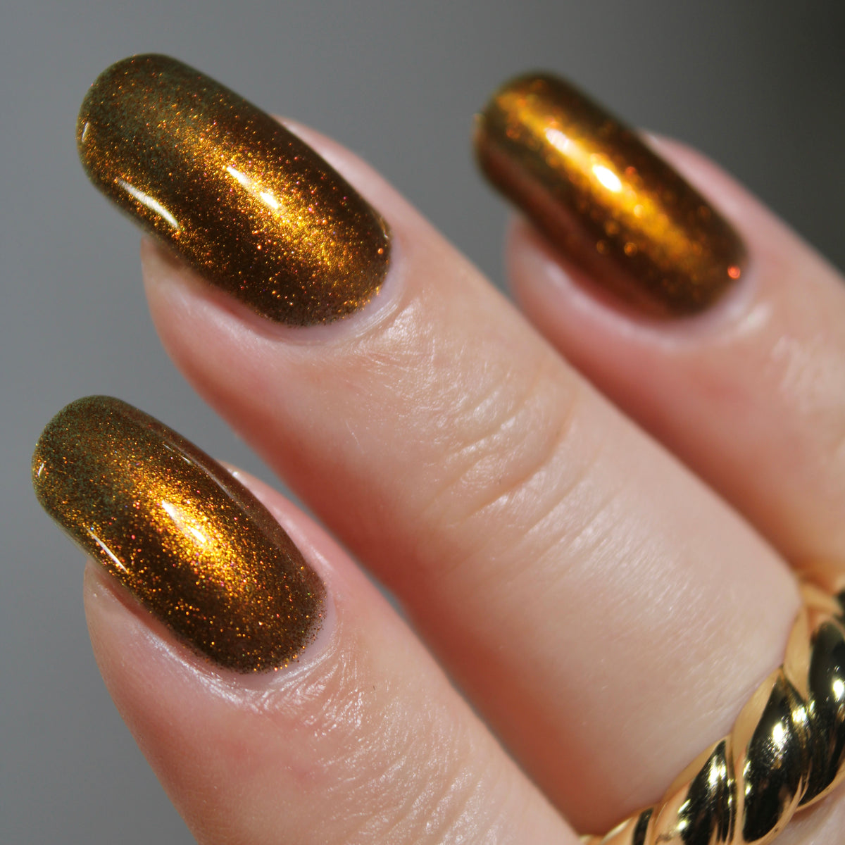 A up close photo of a hand with a copper shimmer manicure.