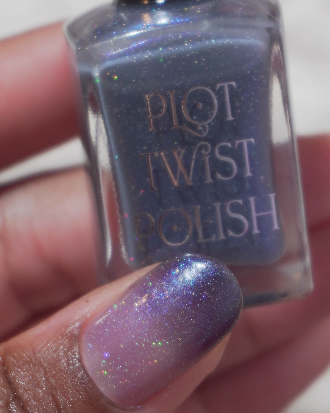 A close up photo of a thumb wearing a transitioning translucent base and blue tip polish and holding a nail polish bottle.