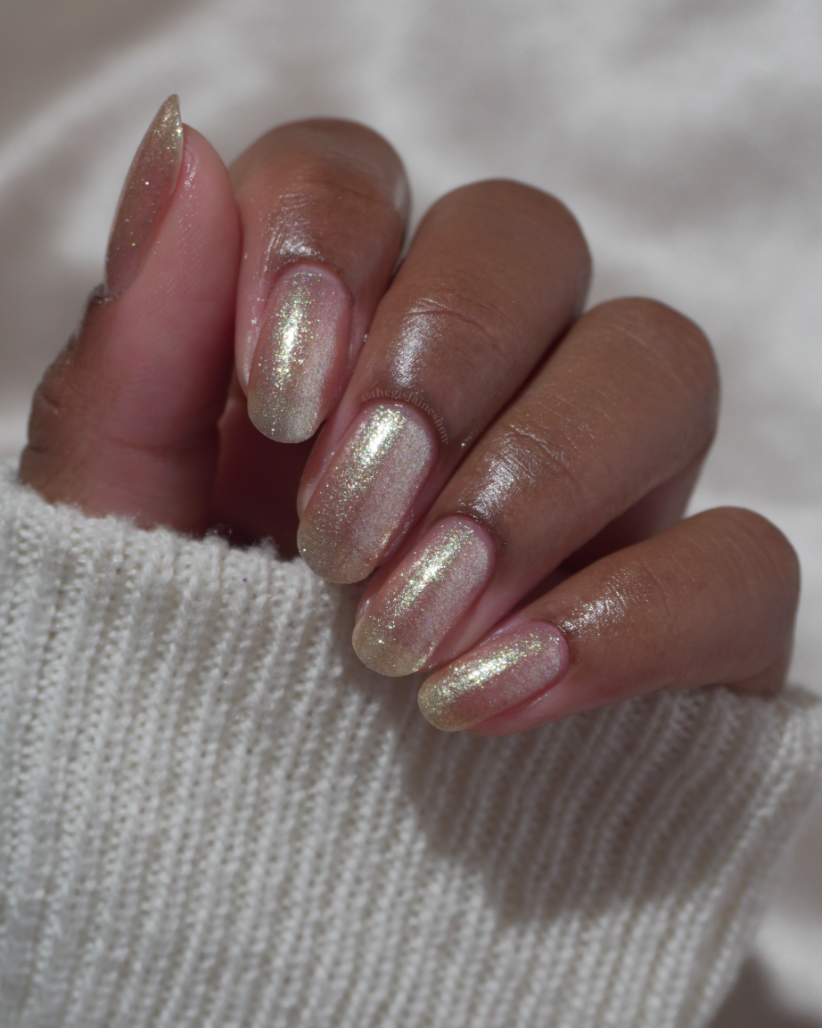 A manicured hand wearing a champagne gold nail polish.