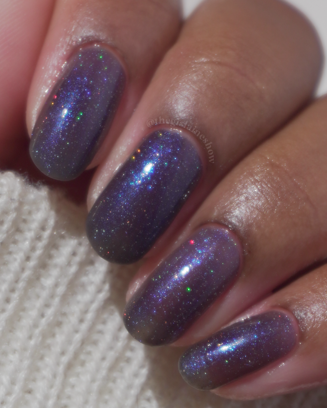 A manicured hand with a blue shimmery nail polish.