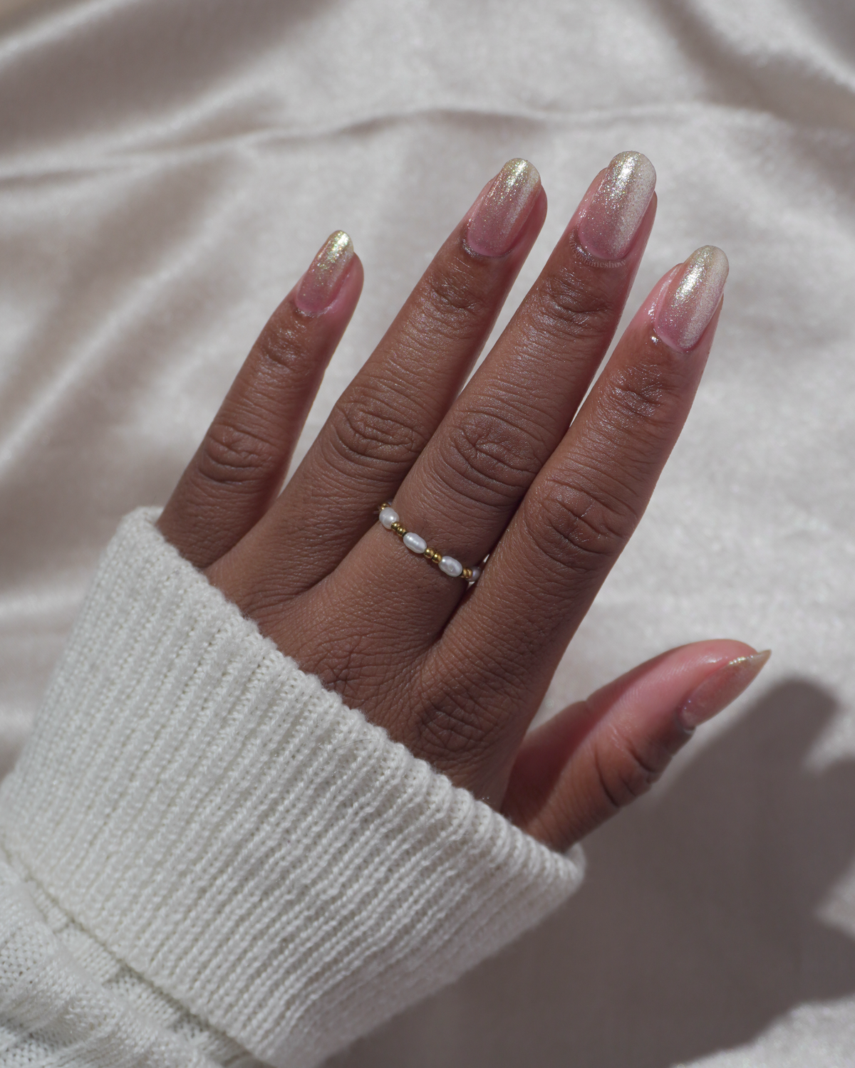 A manicured hand wearing a champagne gold nail polish.