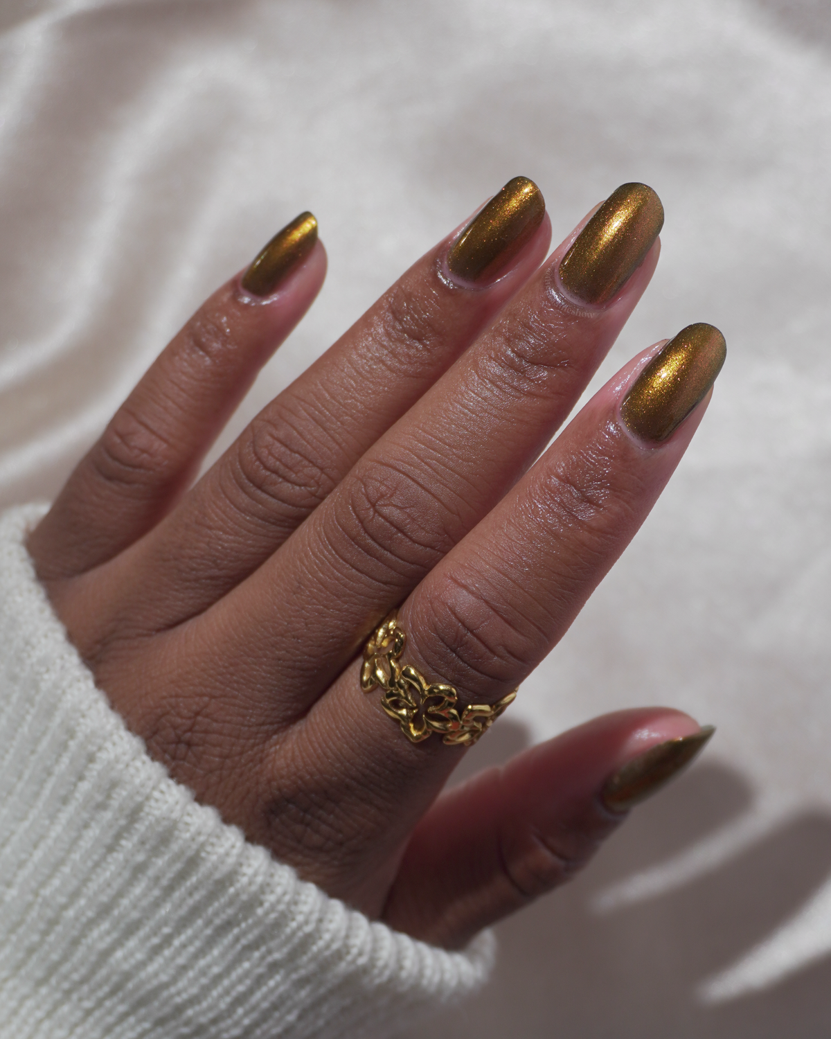 A hand with a copper shimmer manicure. 