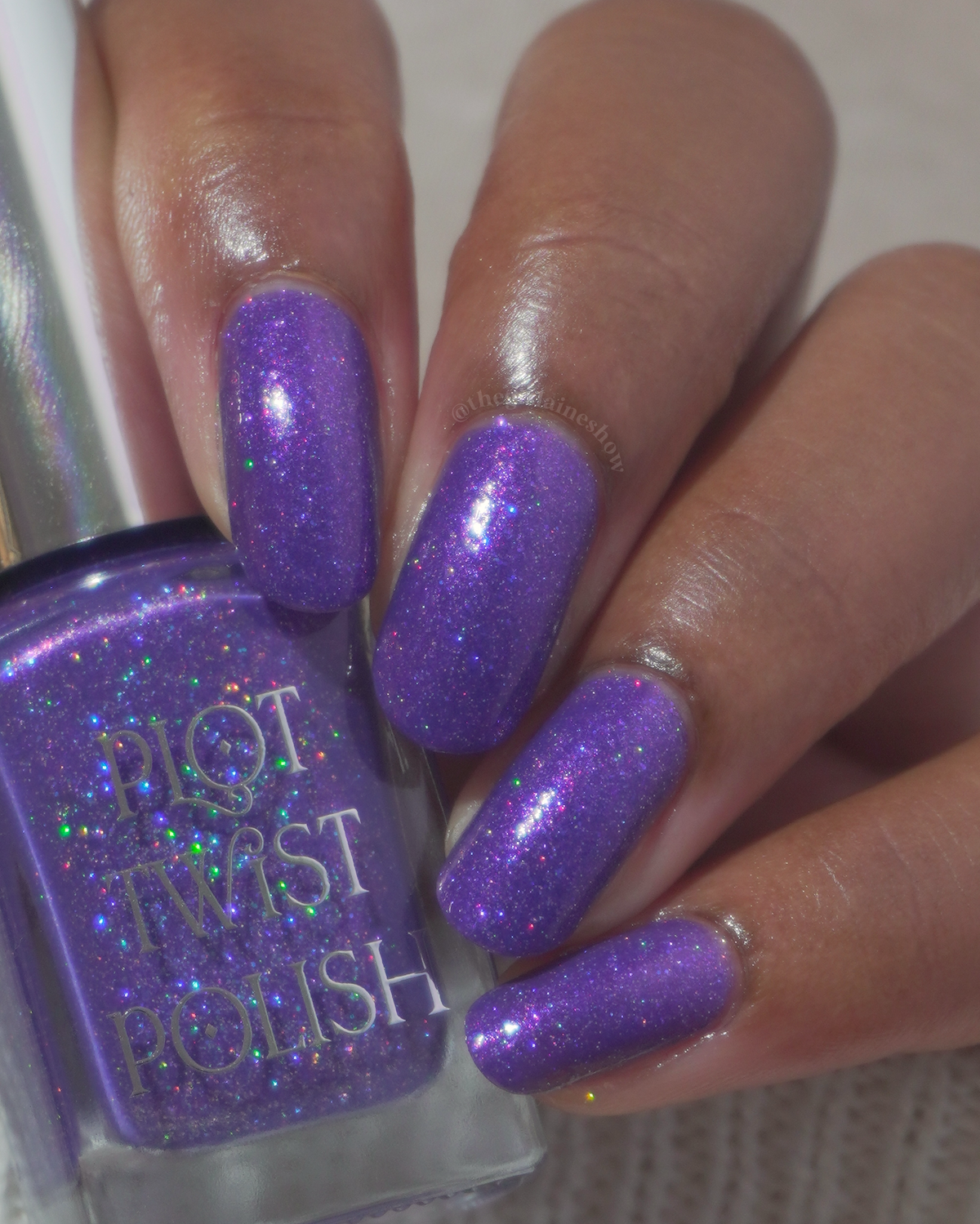 A close-up of a hand with nails painted in a sparkling purple nail polish, shown next to the bottle of Plot Twist Polish in the same glittery purple shade.