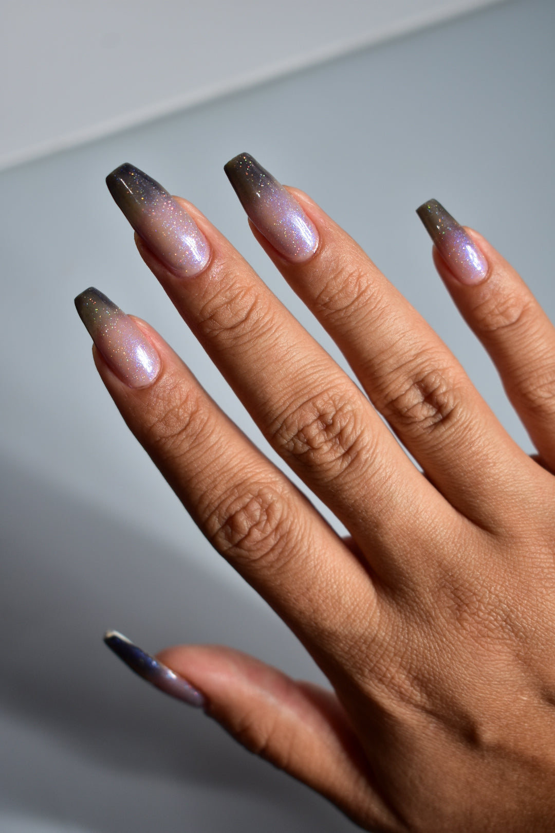 A manicured hand with a translucent shimmery nail polish base and blue nail tips.