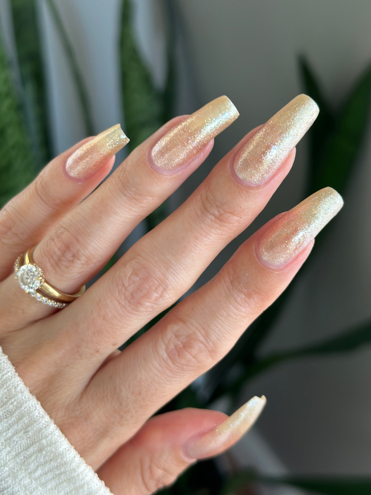 A manicured hand wearing a champagne gold nail polish.