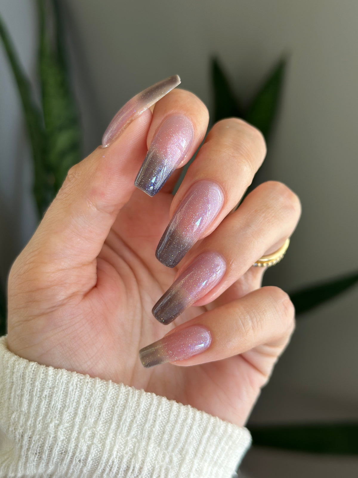 A manicured hand with a translucent shimmery nail polish base and blue nail tips.