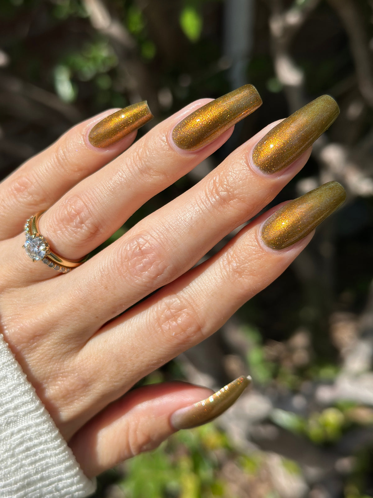 A hand with a copper shimmer manicure. 