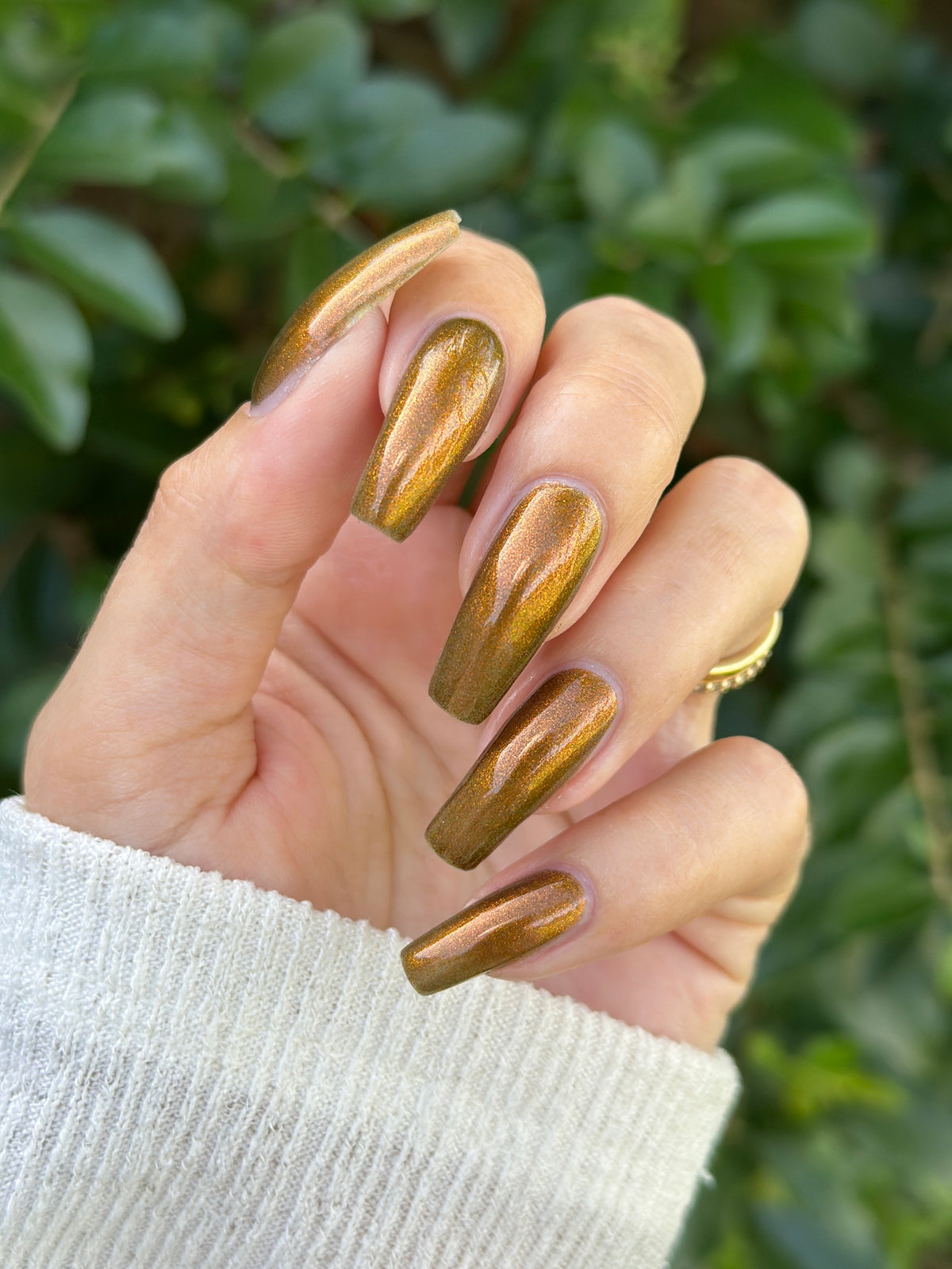A hand with a copper shimmer manicure. 