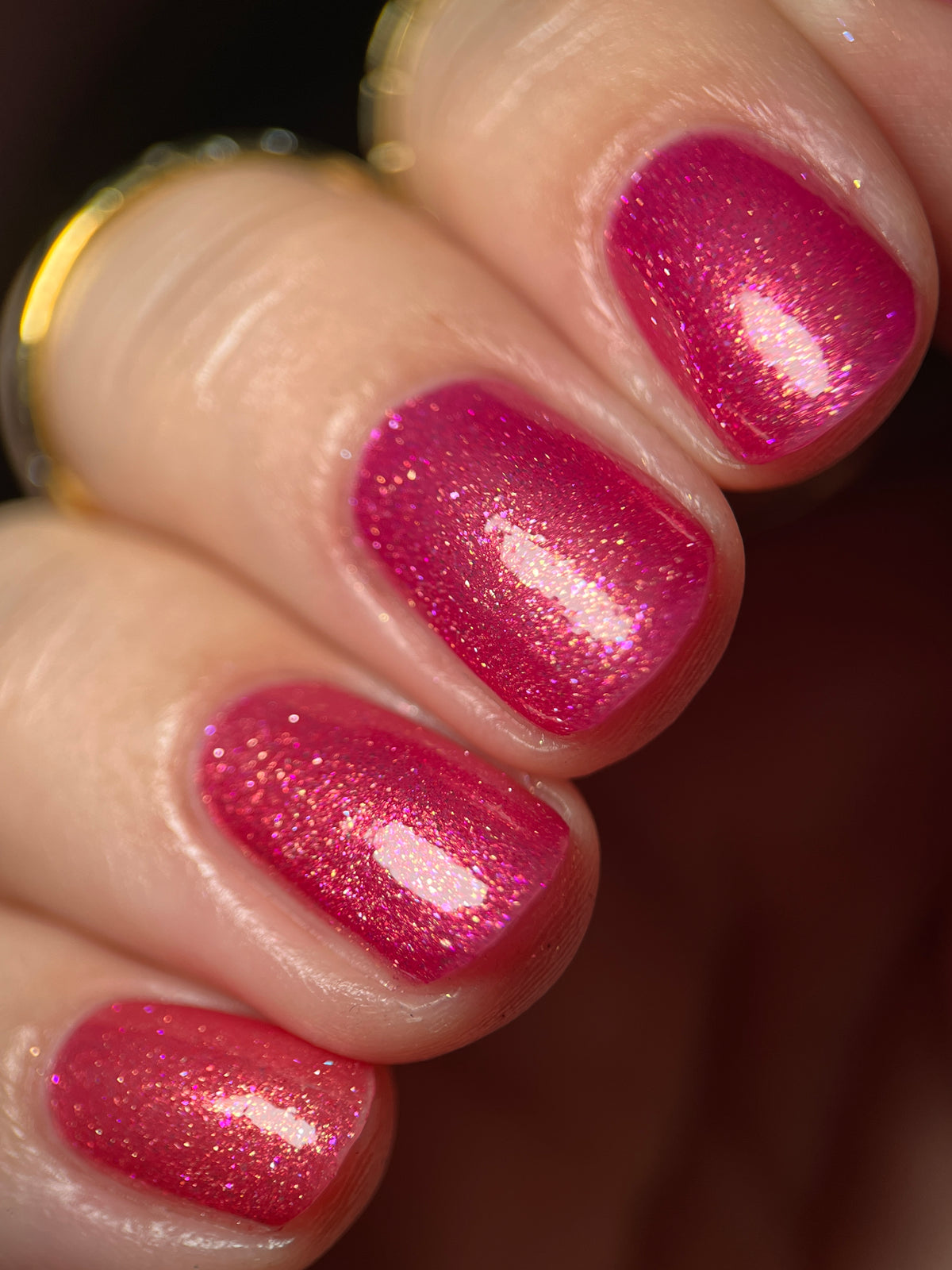 Close-up of fingernails painted with a sparkling pink nail polish showing a fine glitter finish.