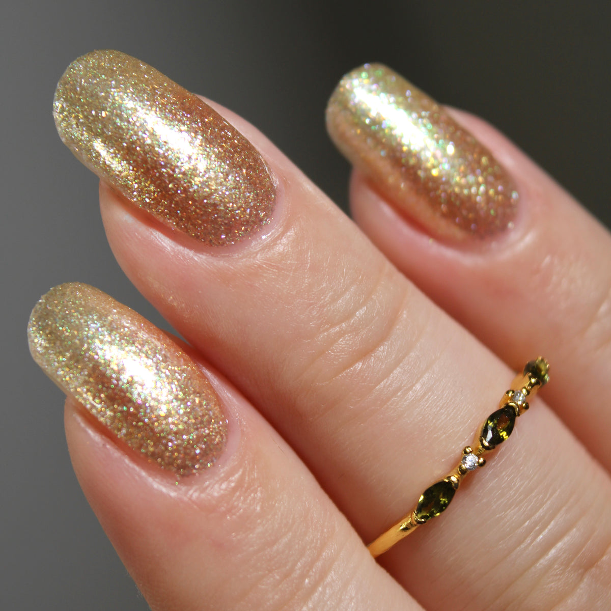 A manicured hand wearing a champagne gold nail polish.