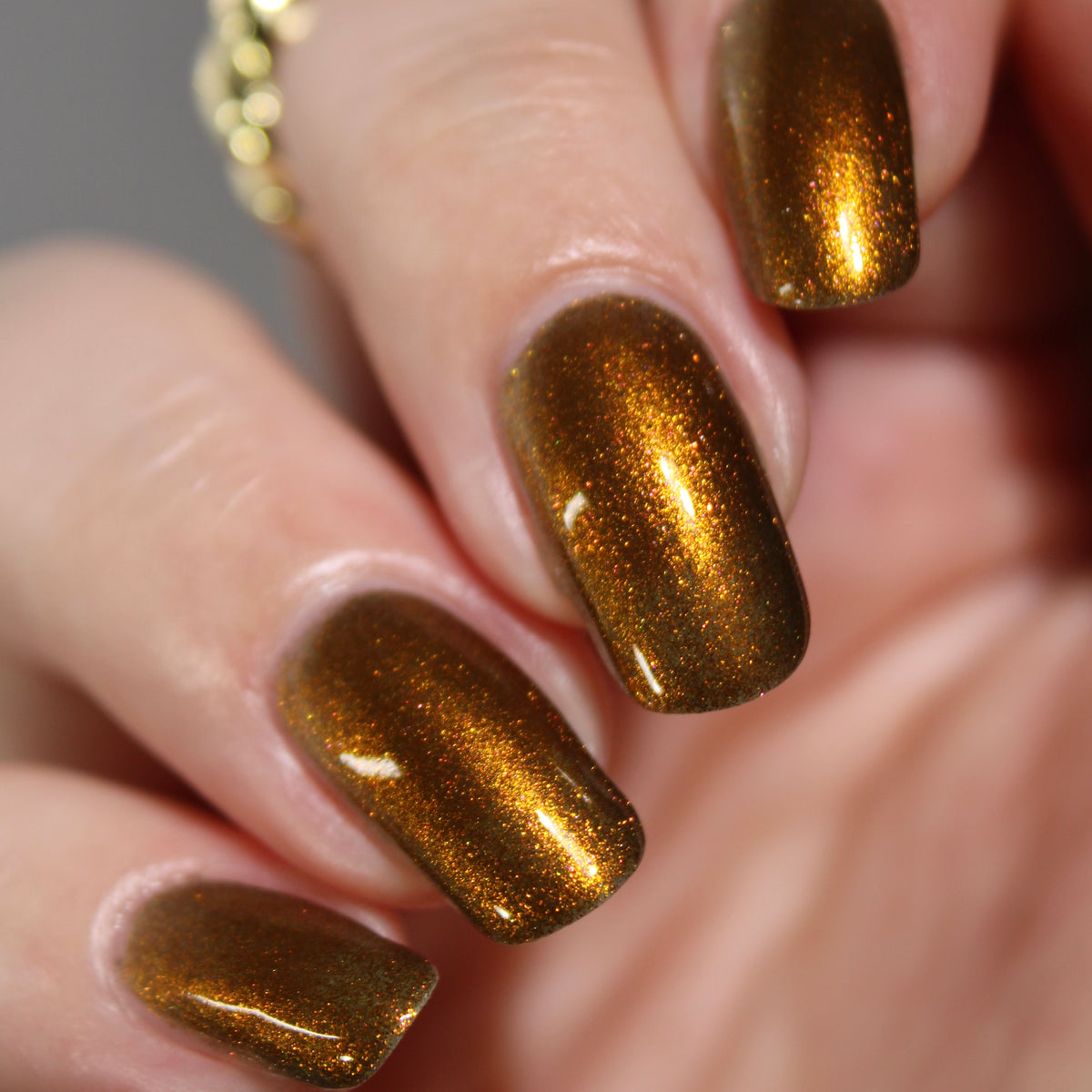 An up close photo of a hand with a copper shimmer manicure. 