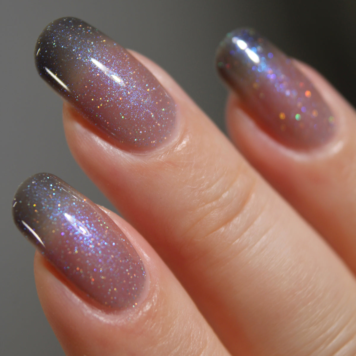 A manicured hand with a translucent shimmery nail polish base and blue nail tips.