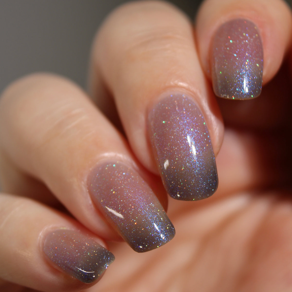 A manicured hand with a translucent shimmery nail polish base and blue nail tips.