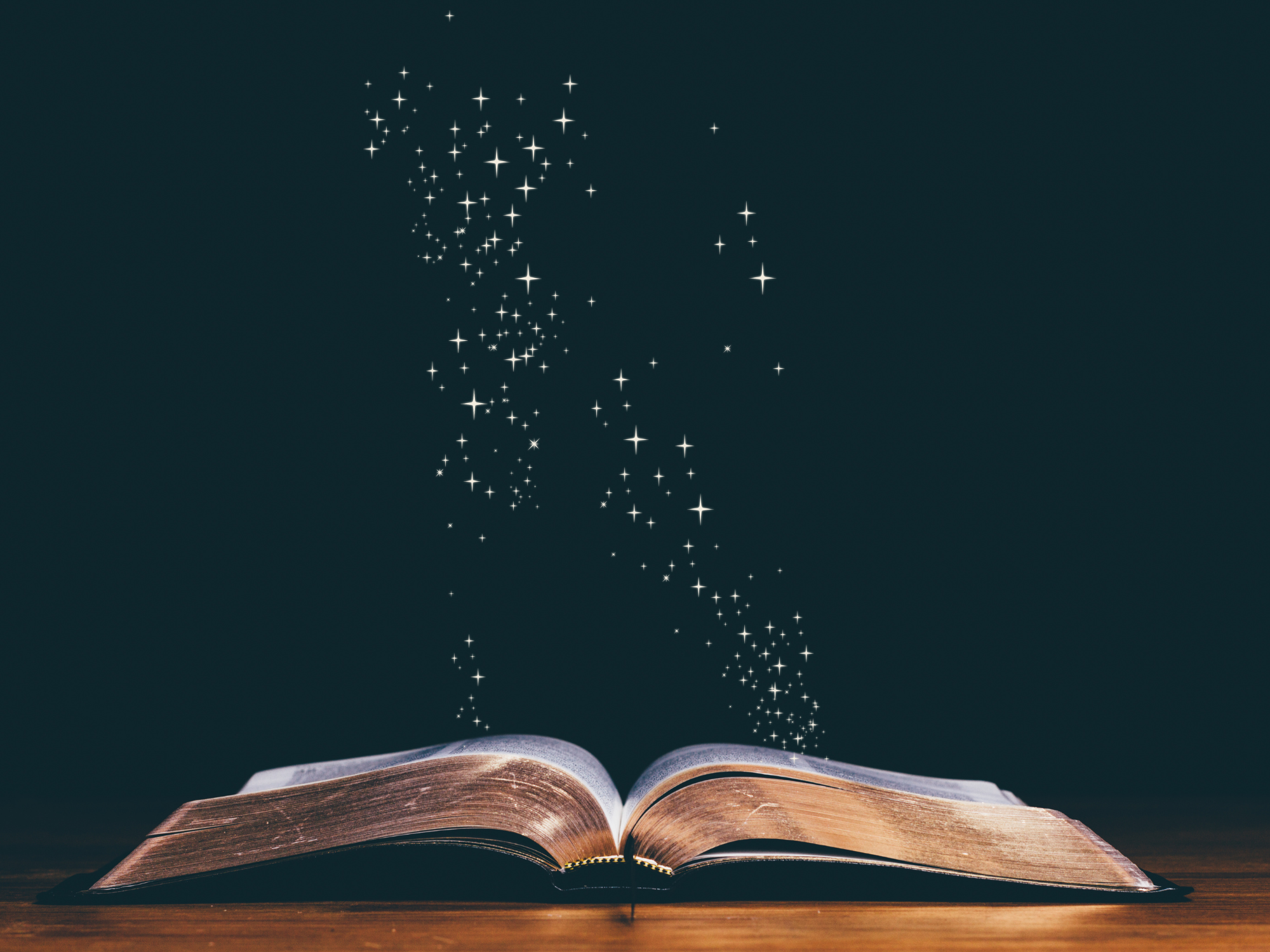 Open book with magical star dust on a dark background