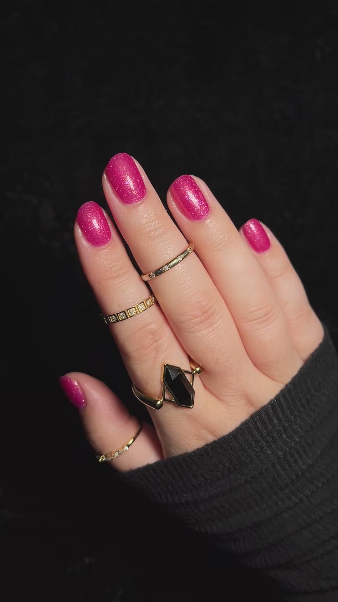A hand with pink glittery polish wiggling to show the shimmer.