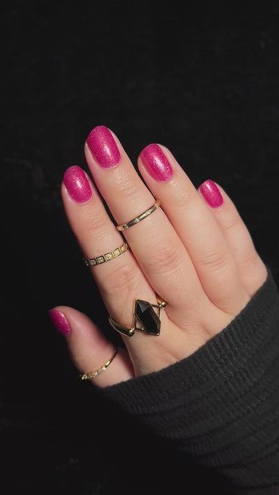 A hand with pink glittery polish wiggling to show the shimmer.
